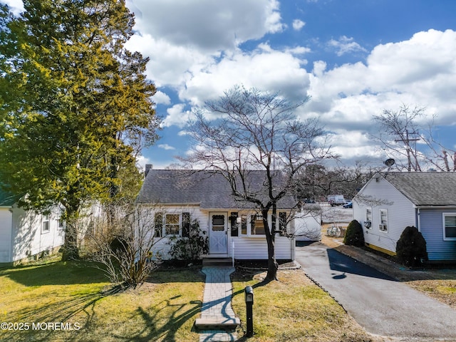 view of front of property with a front yard, roof with shingles, and aphalt driveway