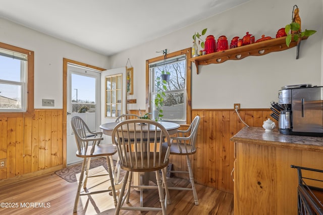 dining room featuring light wood-style flooring, a wainscoted wall, and wood walls