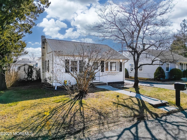 view of front of home with a shingled roof and a front lawn