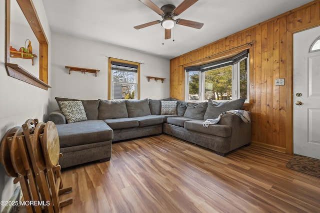 living room featuring wood finished floors, a ceiling fan, and wood walls