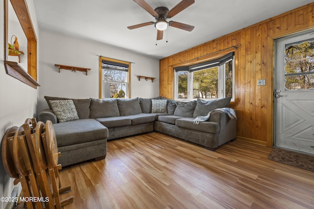 living room with a wealth of natural light, wood walls, and light wood finished floors