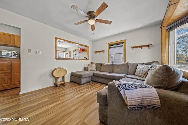 living area featuring light wood-type flooring, baseboards, and a ceiling fan