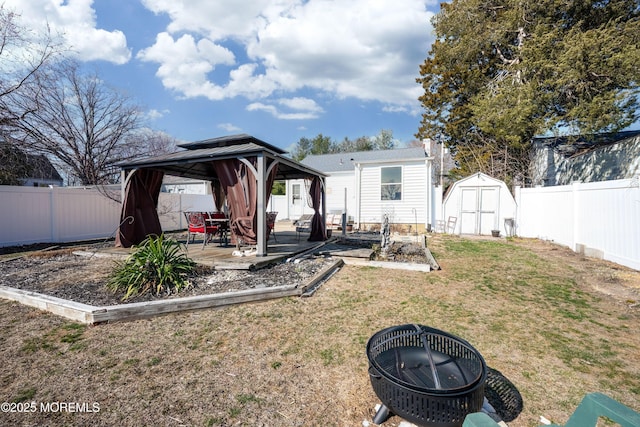 view of yard featuring a gazebo, a storage shed, a fenced backyard, and an outdoor structure