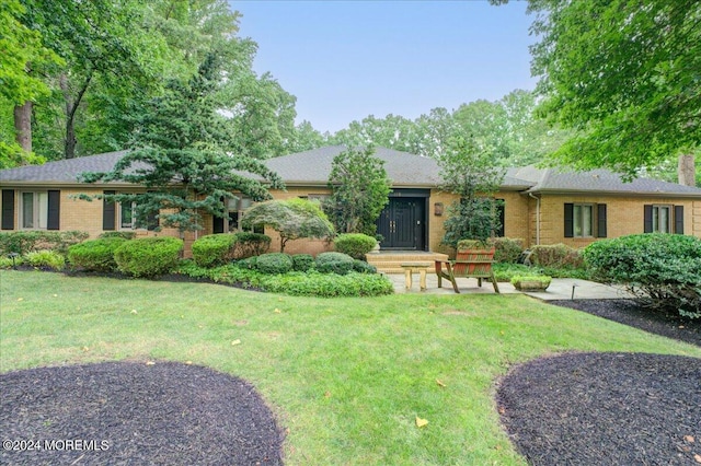 single story home with brick siding, a chimney, and a front lawn