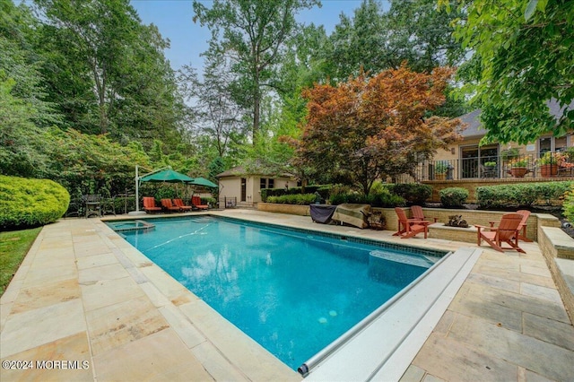 view of swimming pool featuring a pool with connected hot tub, a fire pit, and a patio