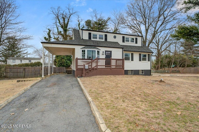 view of front of home with aphalt driveway, fence, a front lawn, and a shingled roof