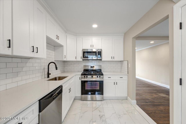 kitchen with baseboards, a sink, marble finish floor, appliances with stainless steel finishes, and tasteful backsplash