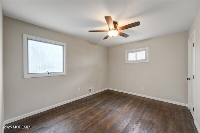 unfurnished room with dark wood-style floors, visible vents, ceiling fan, and baseboards