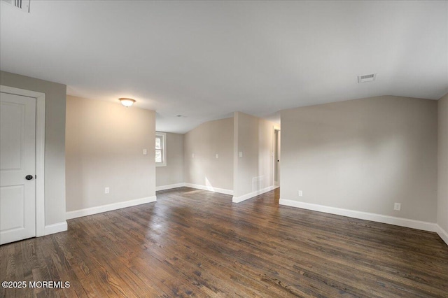 unfurnished room with dark wood-type flooring, visible vents, and baseboards