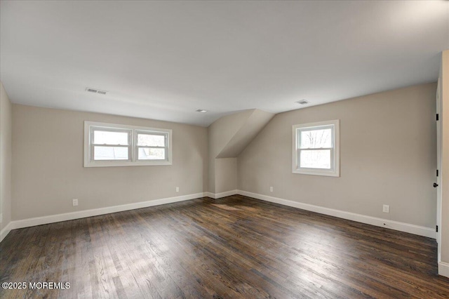 additional living space featuring vaulted ceiling, wood finished floors, visible vents, and baseboards