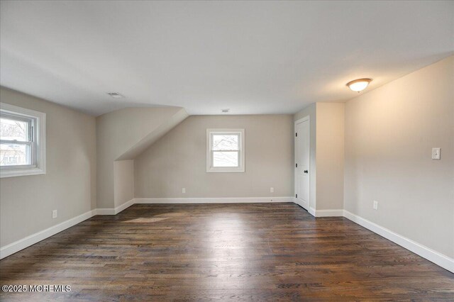 additional living space featuring visible vents, dark wood-type flooring, and baseboards