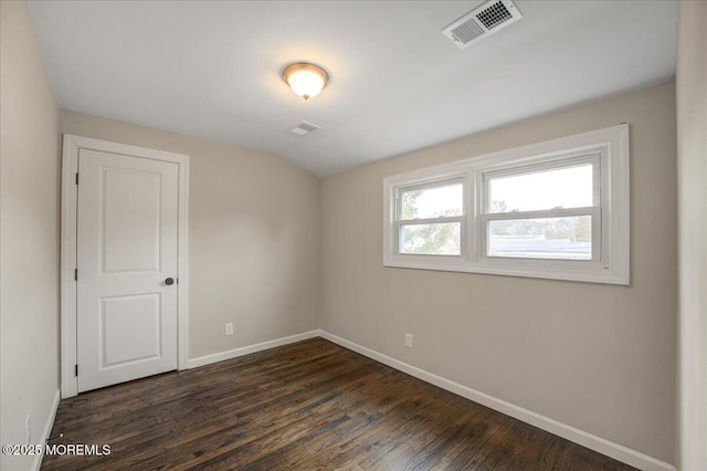 unfurnished room with dark wood-style floors, visible vents, baseboards, and vaulted ceiling