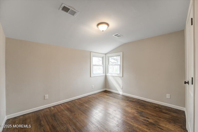 spare room with dark wood-style floors, visible vents, baseboards, and vaulted ceiling