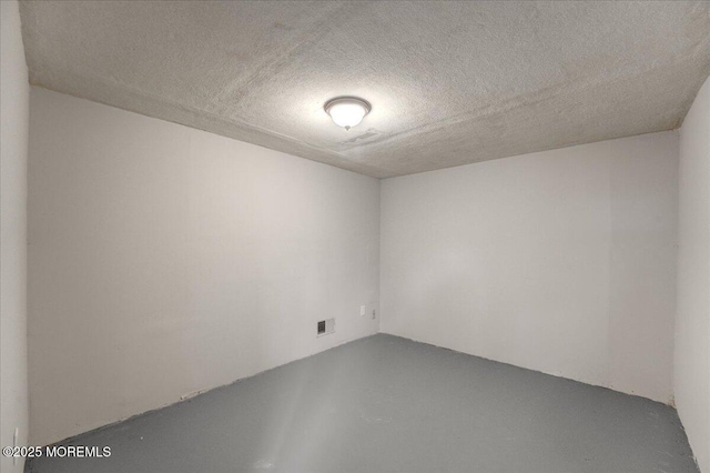 unfurnished room featuring visible vents, concrete flooring, and a textured ceiling