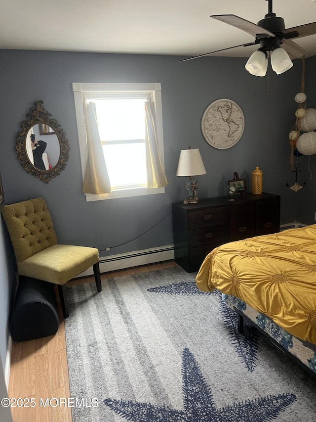 bedroom featuring a baseboard heating unit, a ceiling fan, and wood finished floors