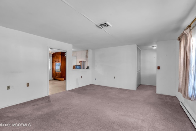 spare room featuring a baseboard heating unit, visible vents, and light carpet