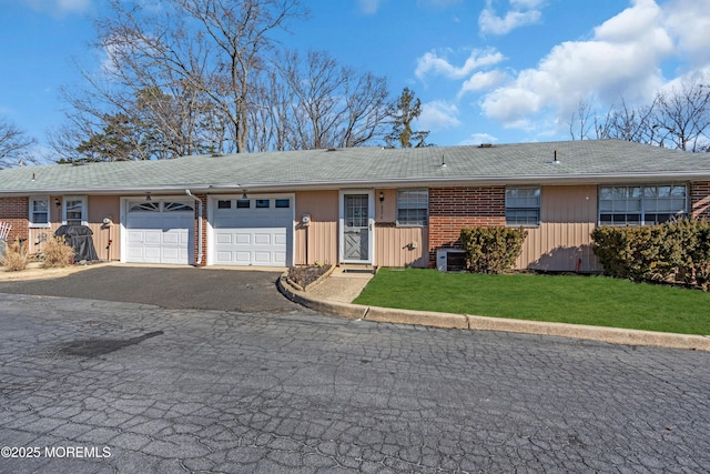 single story home with a front yard, cooling unit, an attached garage, aphalt driveway, and brick siding