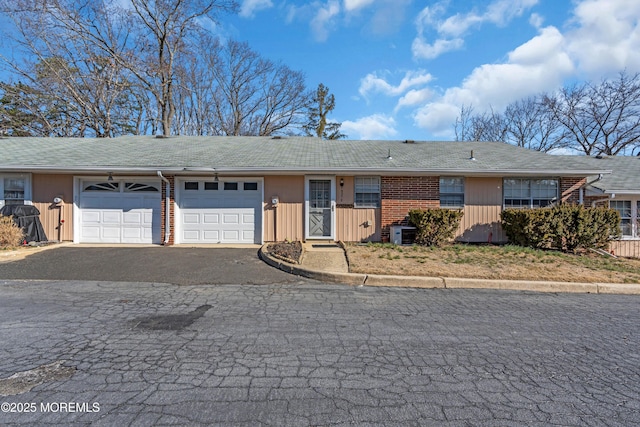 view of front of property featuring aphalt driveway, central air condition unit, and an attached garage