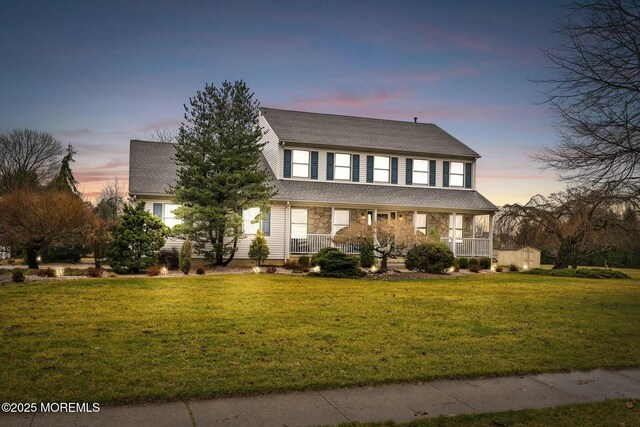 traditional home with a front lawn, covered porch, and roof with shingles