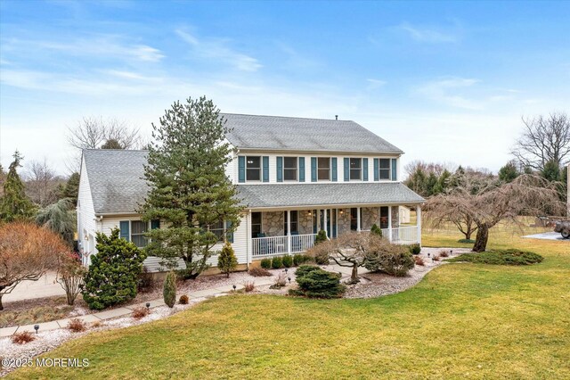 colonial-style house with stone siding, roof with shingles, a porch, and a front lawn