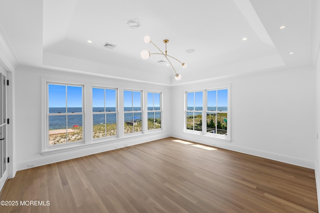 interior space with a notable chandelier, a raised ceiling, baseboards, and wood finished floors