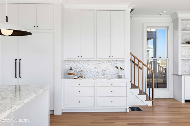 kitchen featuring light stone counters, light wood-type flooring, tasteful backsplash, and white cabinets