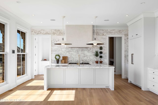 kitchen featuring hanging light fixtures, white cabinets, light stone counters, and light wood finished floors