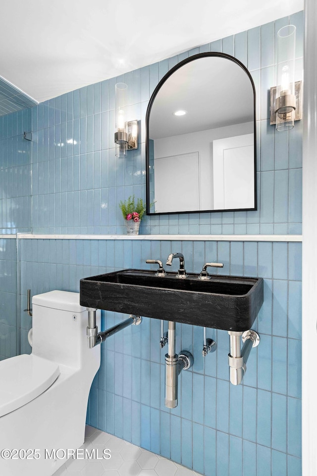 bathroom featuring tile patterned floors, toilet, and tile walls