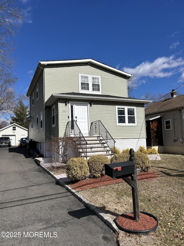 view of front of house with a garage and an outbuilding