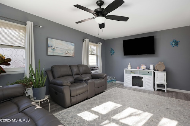 living area featuring a glass covered fireplace, baseboards, and wood finished floors