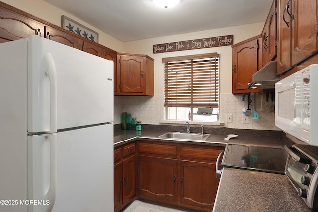 kitchen with dark countertops, backsplash, white appliances, and a sink