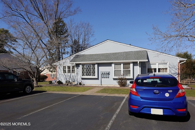 view of front of home with uncovered parking and a shingled roof