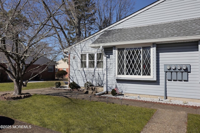 property entrance featuring a lawn and roof with shingles