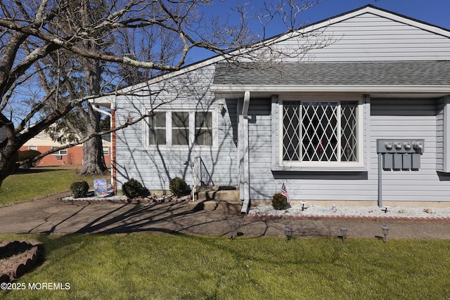 view of front of house featuring a front yard and a shingled roof