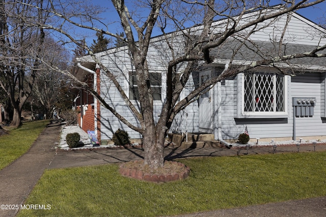 view of front of home with a front yard and a shingled roof