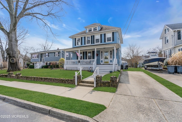 american foursquare style home featuring driveway, a porch, and a front yard