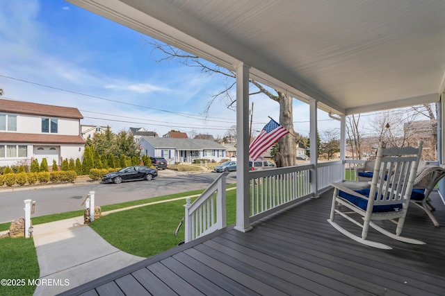 wooden terrace with a residential view, covered porch, and a yard