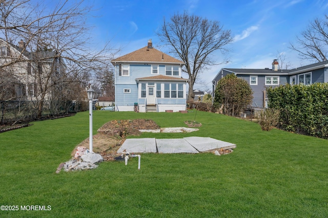 rear view of property featuring a yard, a chimney, and a sunroom