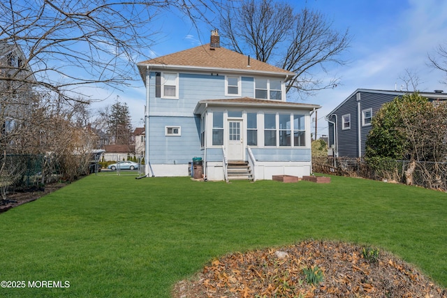 rear view of property featuring fence, a lawn, a chimney, and a sunroom