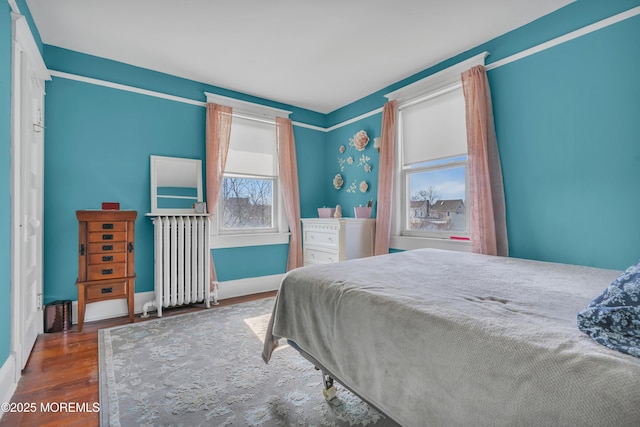 bedroom with baseboards, wood finished floors, and radiator heating unit