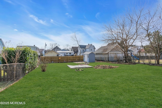 view of yard featuring a fenced backyard, a storage shed, an outdoor structure, and a playground