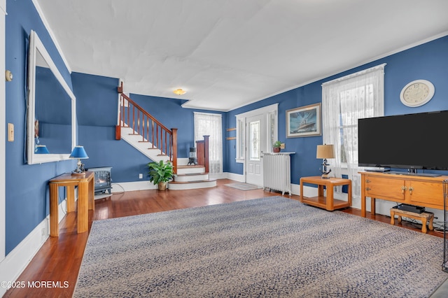 living room featuring radiator, stairs, baseboards, and wood finished floors