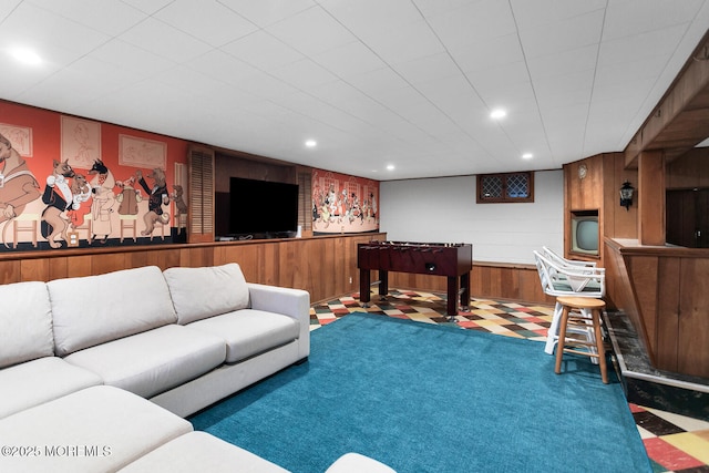 carpeted living area with wooden walls and recessed lighting