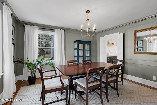 dining area with an inviting chandelier, crown molding, baseboards, and light wood-type flooring