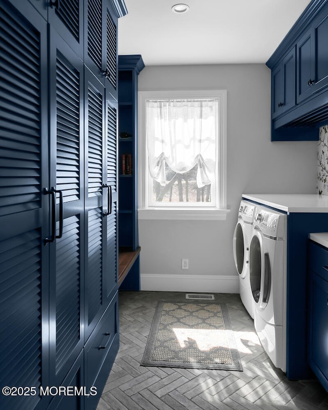 clothes washing area with baseboards, cabinet space, visible vents, and washer and clothes dryer