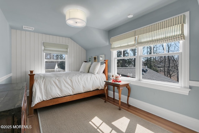 bedroom with visible vents, baseboards, lofted ceiling, and wood finished floors