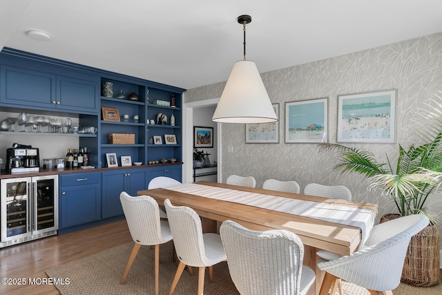 dining room featuring wine cooler, wallpapered walls, indoor bar, and wood finished floors