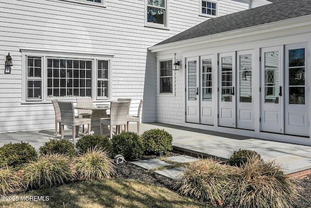 exterior space with a shingled roof and a patio