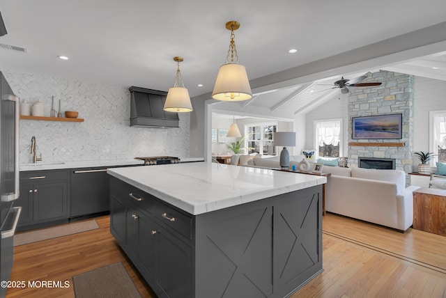 kitchen featuring a sink, light wood-style floors, dishwasher, and vaulted ceiling with beams