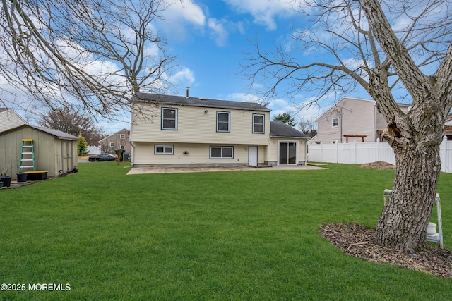 back of property featuring fence, a lawn, a storage shed, an outbuilding, and a patio